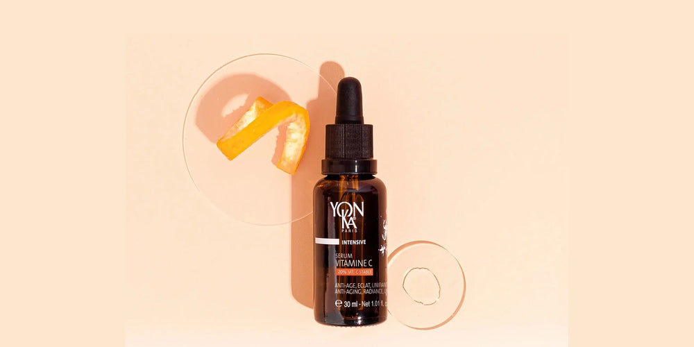 A dropper bottle of Yon-Ka Vitamin C Serum surrounded by sliced oranges and leaves, highlighting its natural ingredients.